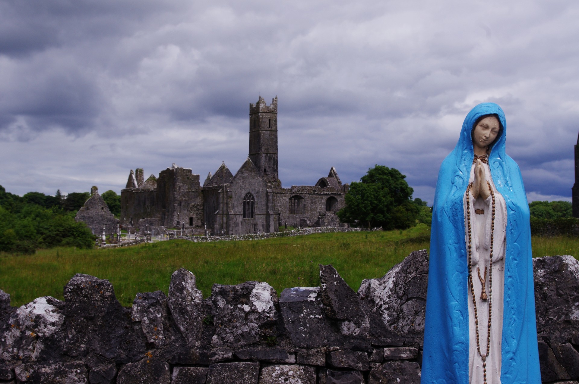 Statue of Mother Mary praying in front of Irish church ruin (Quin, County Clare, Ireland)