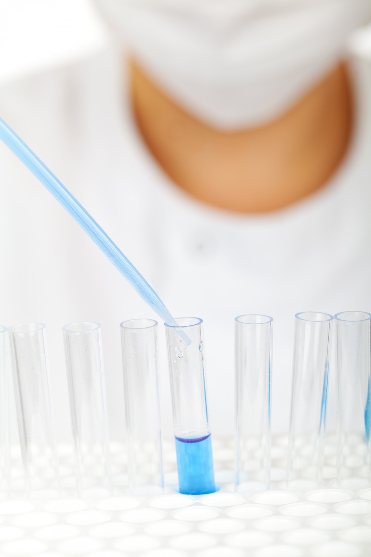 a scientist fills test tubes with blue liquid