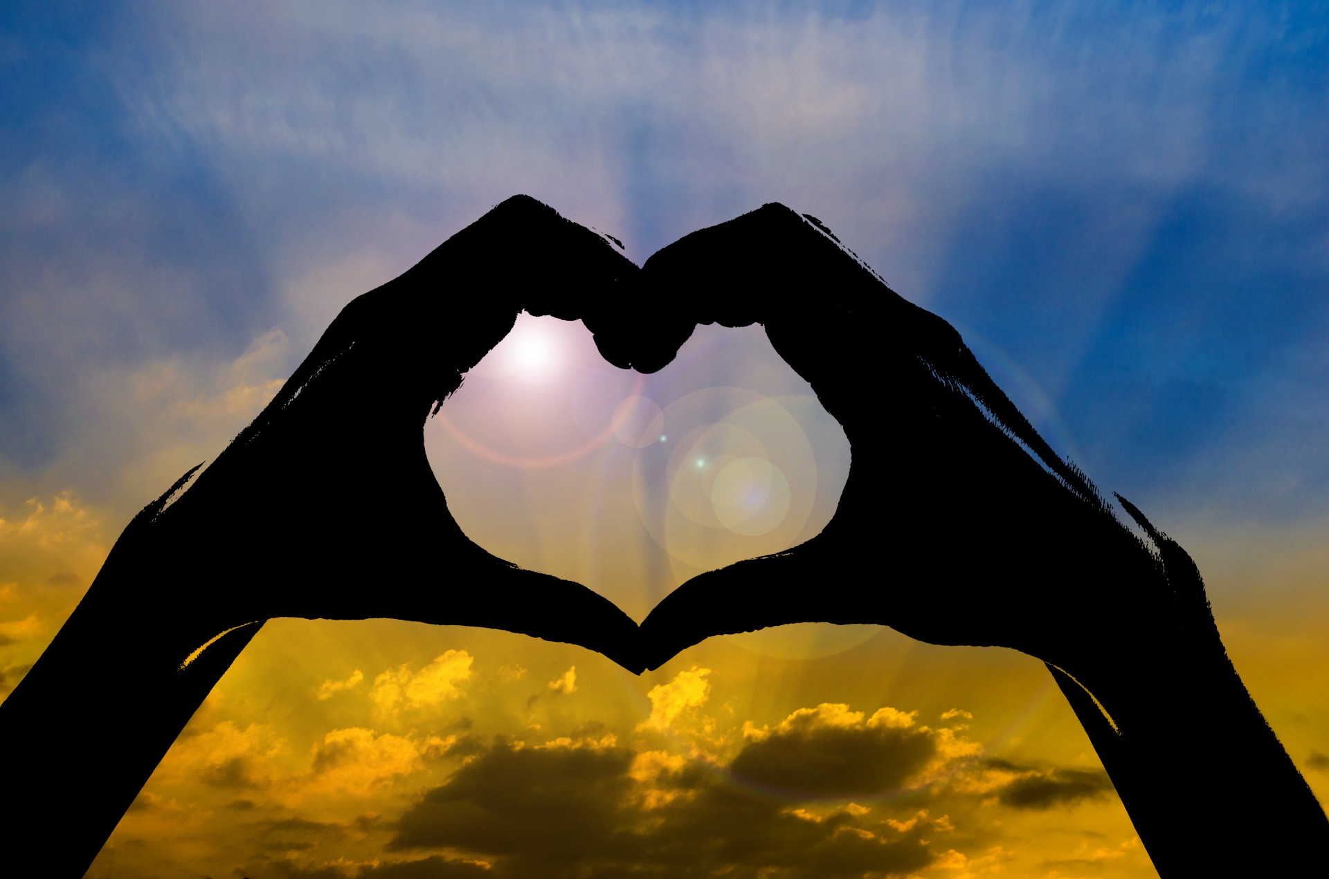 Concept or conceptual heart shape or symbol made of human or woman and man hand silhouette over a sky at sunset background,metaphor to love,valentine,romantic,couple,wedding ,romance,summer or sunrise