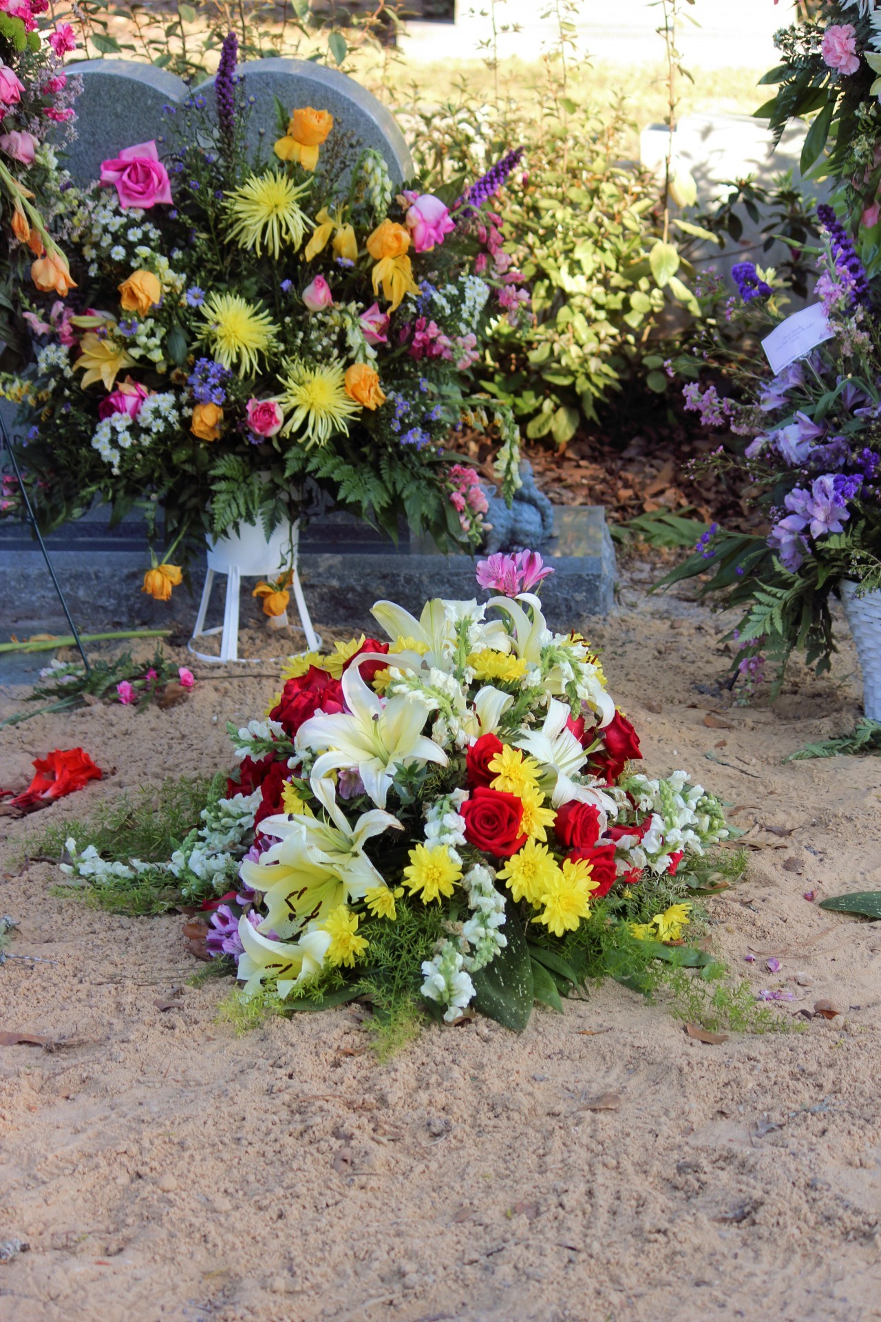 A recent grave site with the dirt freshly piled, and the burial flowers on top.