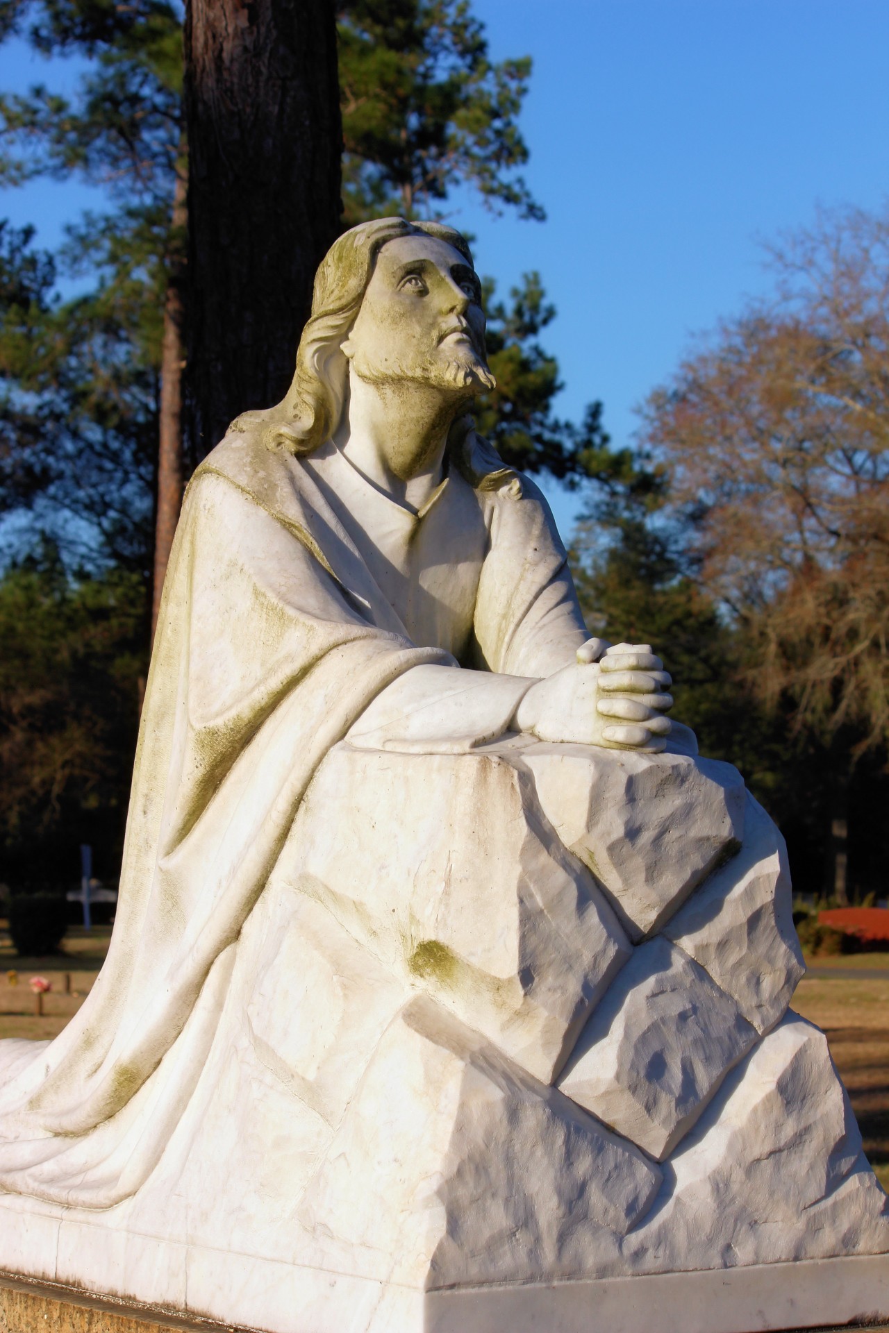 A replica male statue looking upward toward the heaven at a local cemetery.