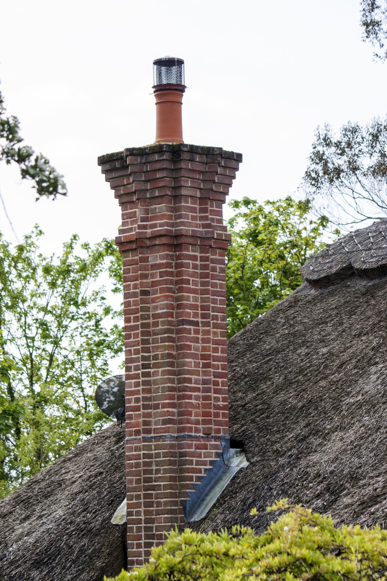 Red brick chimney stack on a thatch roof in close-up details